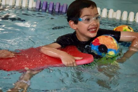 child with disability receiving assistance in a pool