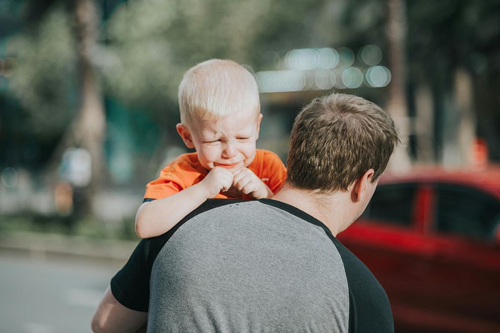 Back-to-School Blues Upset toddler on father's shoulder