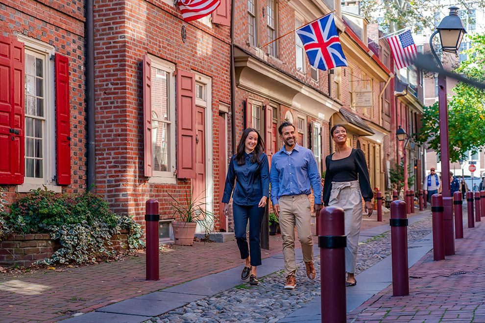 two women and a man walking down an historic street in Philadelphia, PA