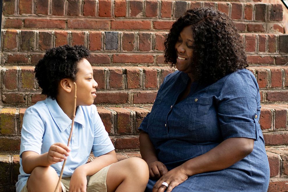A woman smiling and talking with a boy on a set of brick steps