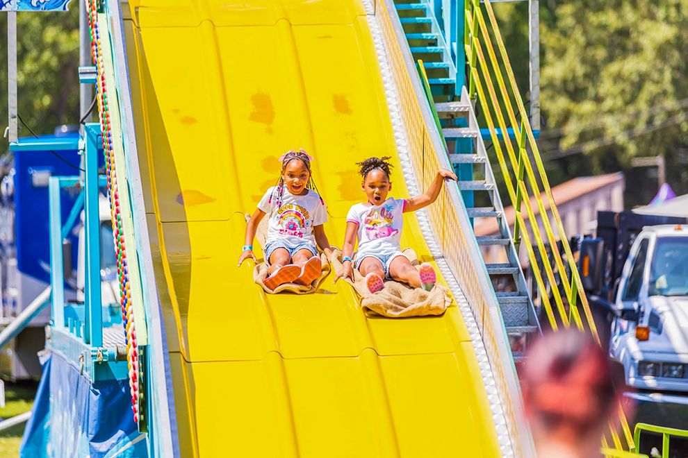 two girls sliding down a giant slide on sacks