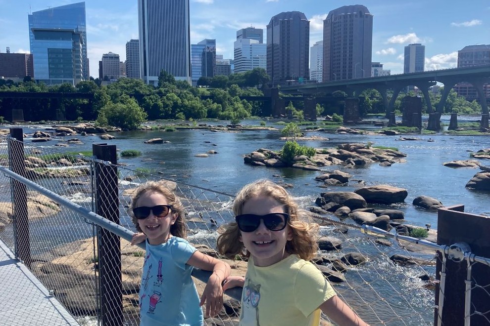 Two girls smiling on the T Potterfield Bridge with Richmond VA skyline behind them