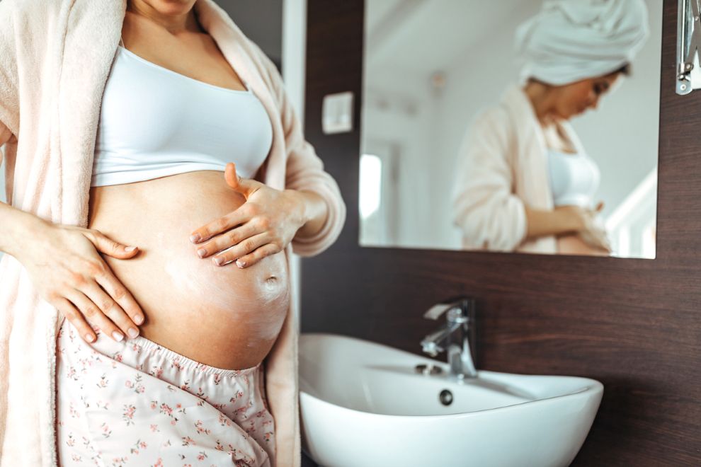 Body Changes to Expect in Each Trimester of Pregnancy a pregnant womans belly in a bathroom VPFW