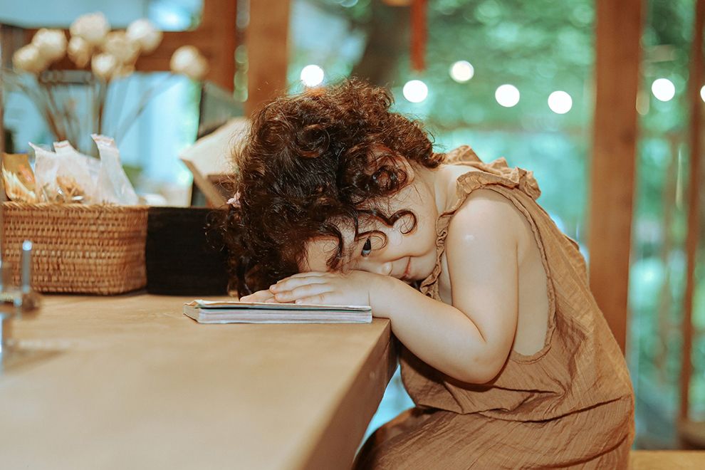 Balancing Act young girl with a book with her head down on the table