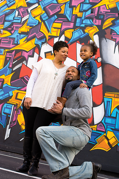 Taekia Glass is program director at ART 180, across the street from this mural. Taekia and Hamilton’s daughter, Sanaa, is riding high on Daddy’s shoulders.